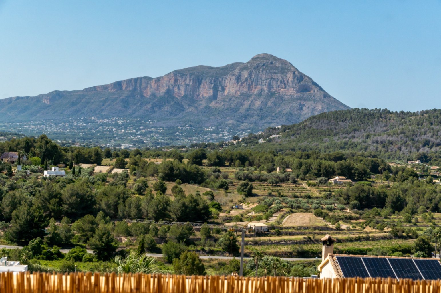 Vistas panorámicas al macizo del Montgó desde la propiedad, destacando el entorno natural de pinos y la instalación de placas solares sobre la cubierta vecina.