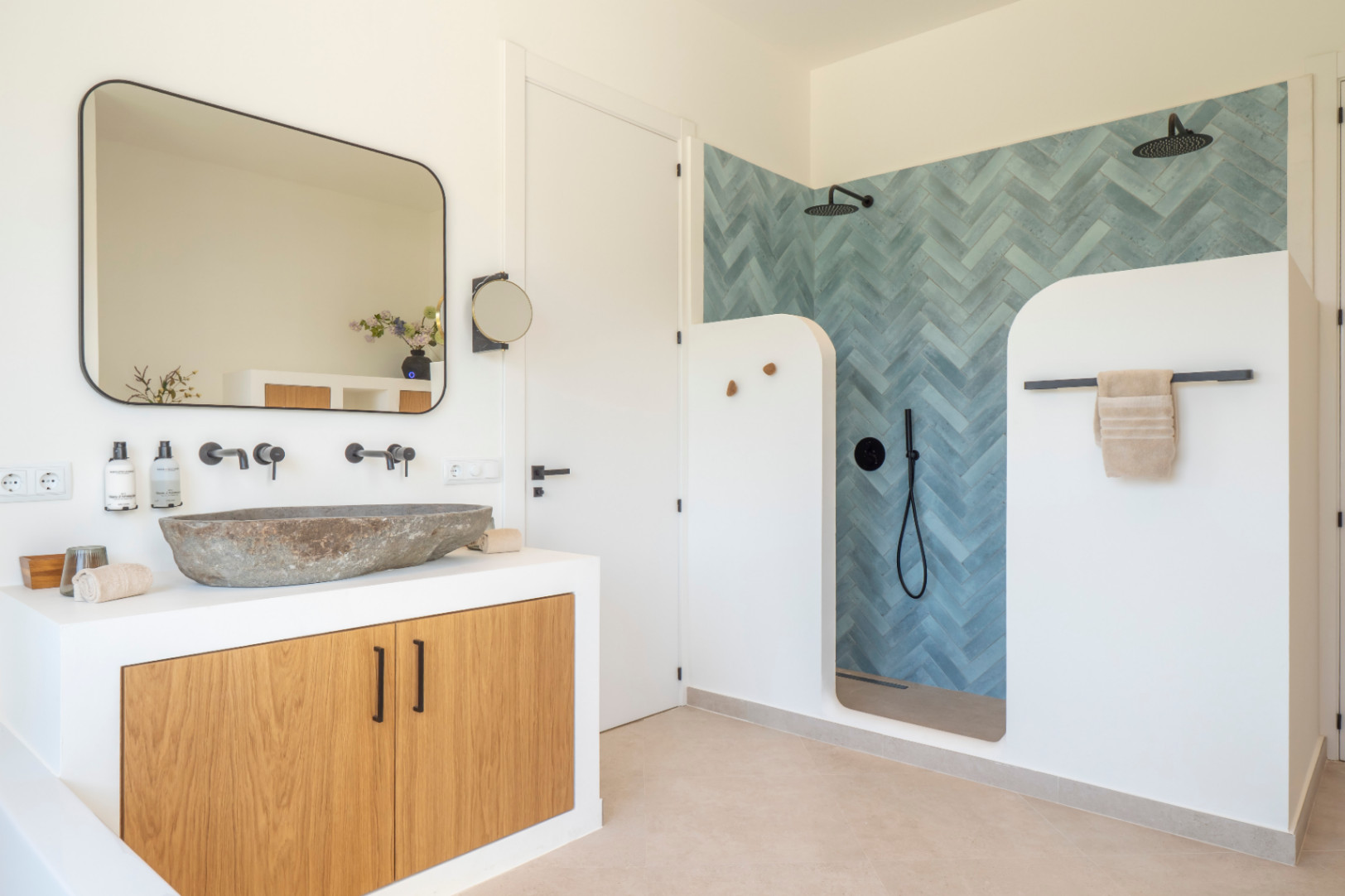Detalle de baño con lavabo de piedra y ducha con azulejos en espiga azul en Villa de Jávea.