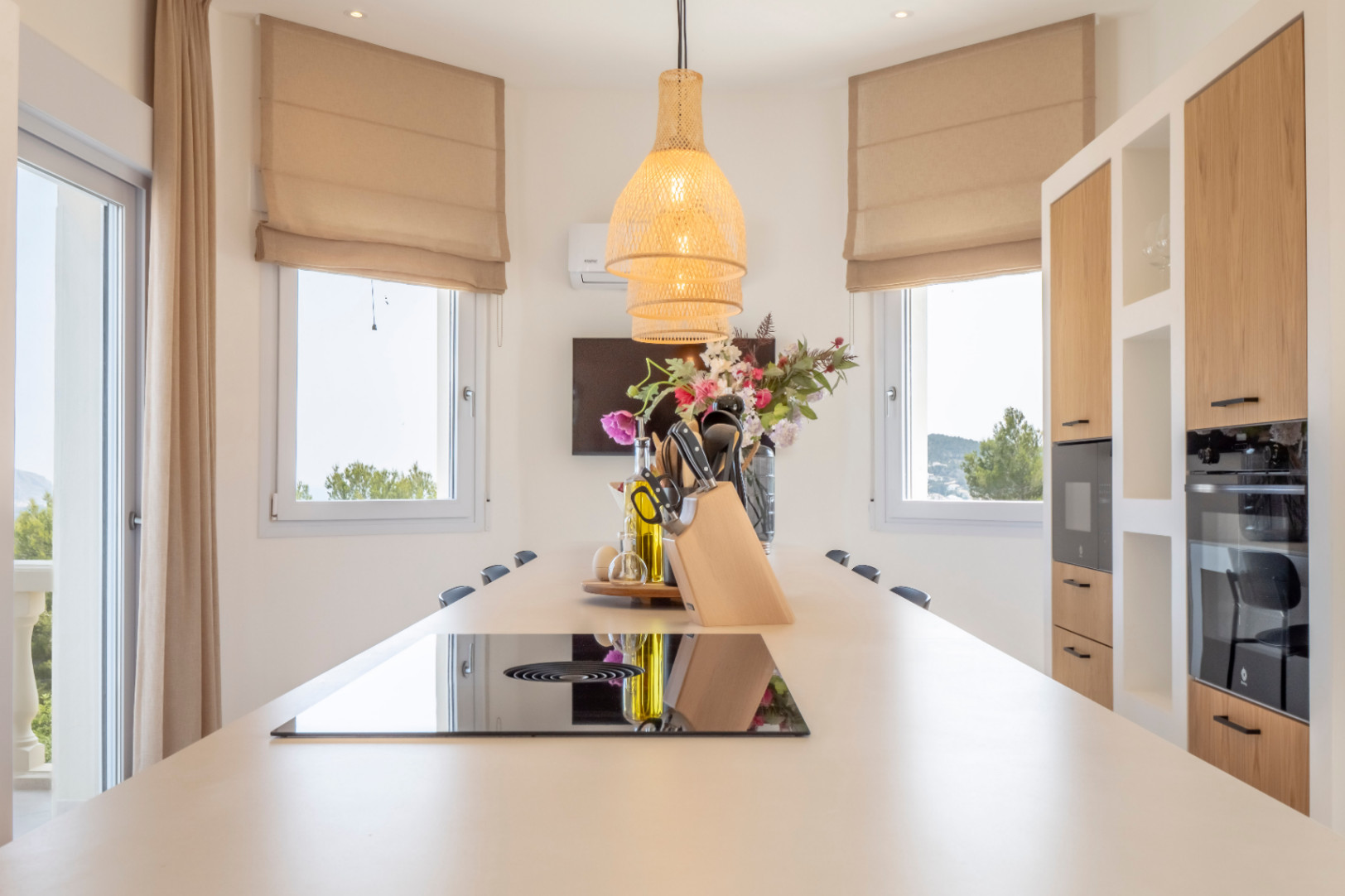 Detalle de la cocina con isla central, placa de inducción y luz colgante de mimbre.