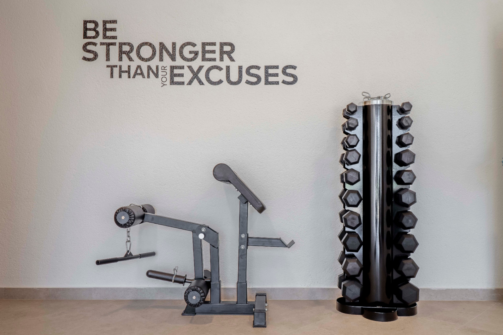 Gimnasio en casa con máquina de ejercicios y estante de mancuernas hexagonales negras.