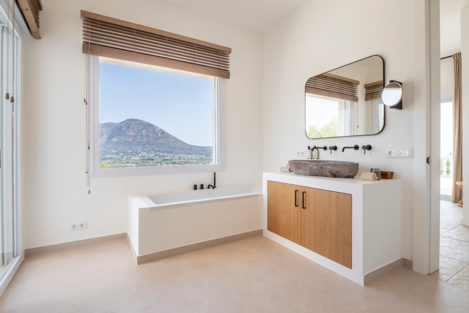 Luminoso baño con lavabo de piedra y vistas a la montaña. Diseño moderno y minimalista.