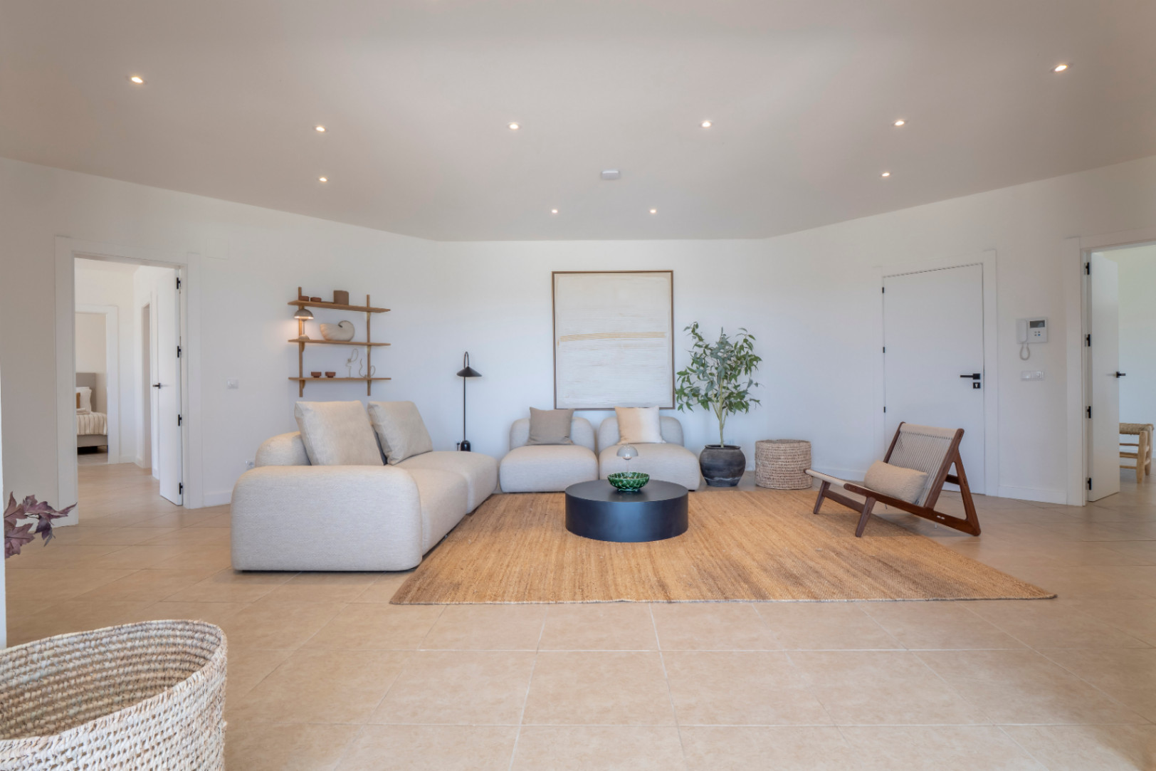 Luminoso salón con sofá modular beige, alfombra de yute y detalles decorativos minimalistas. Iluminación empotrada.
