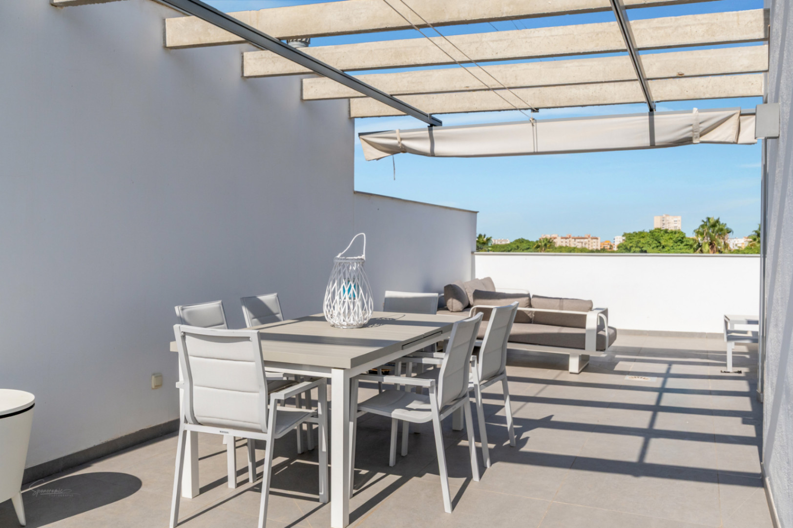 Terraza privada en la azotea con pérgola de hormigón, toldo retráctil y zona de comedor exterior con vistas despejadas al entorno natural.