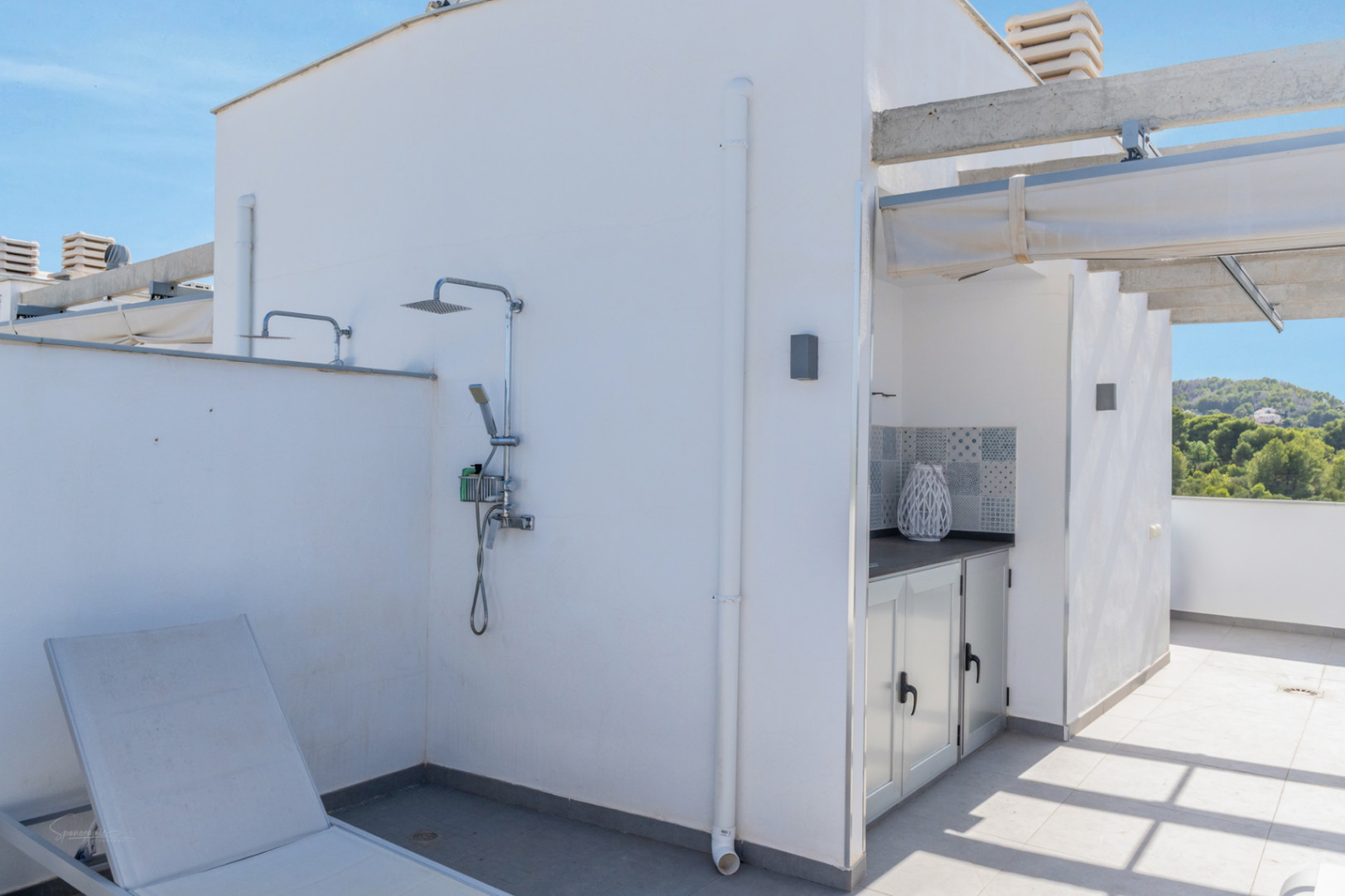 Terraza privada en la azotea equipada con ducha exterior, zona de cocina de verano con azulejos decorativos y pérgola con toldo retráctil.