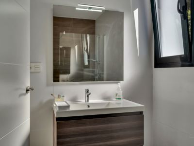 Detalle del baño con lavabo moderno y espejo iluminado.