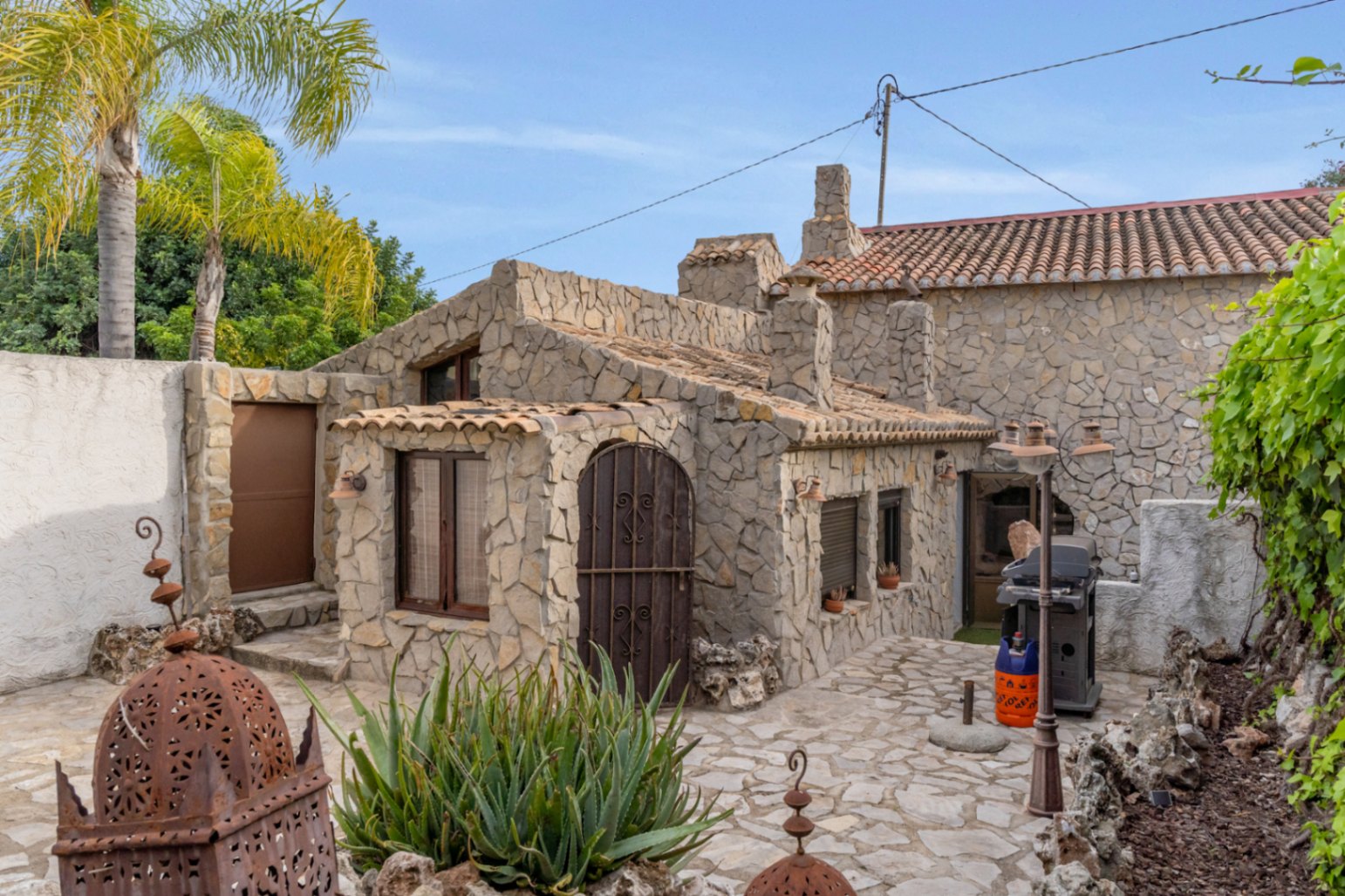 Apartamento de invitados independiente revestido en piedra natural, con patio pavimentado, barbacoa exterior y detalles arquitectónicos tradicionales en Jávea.