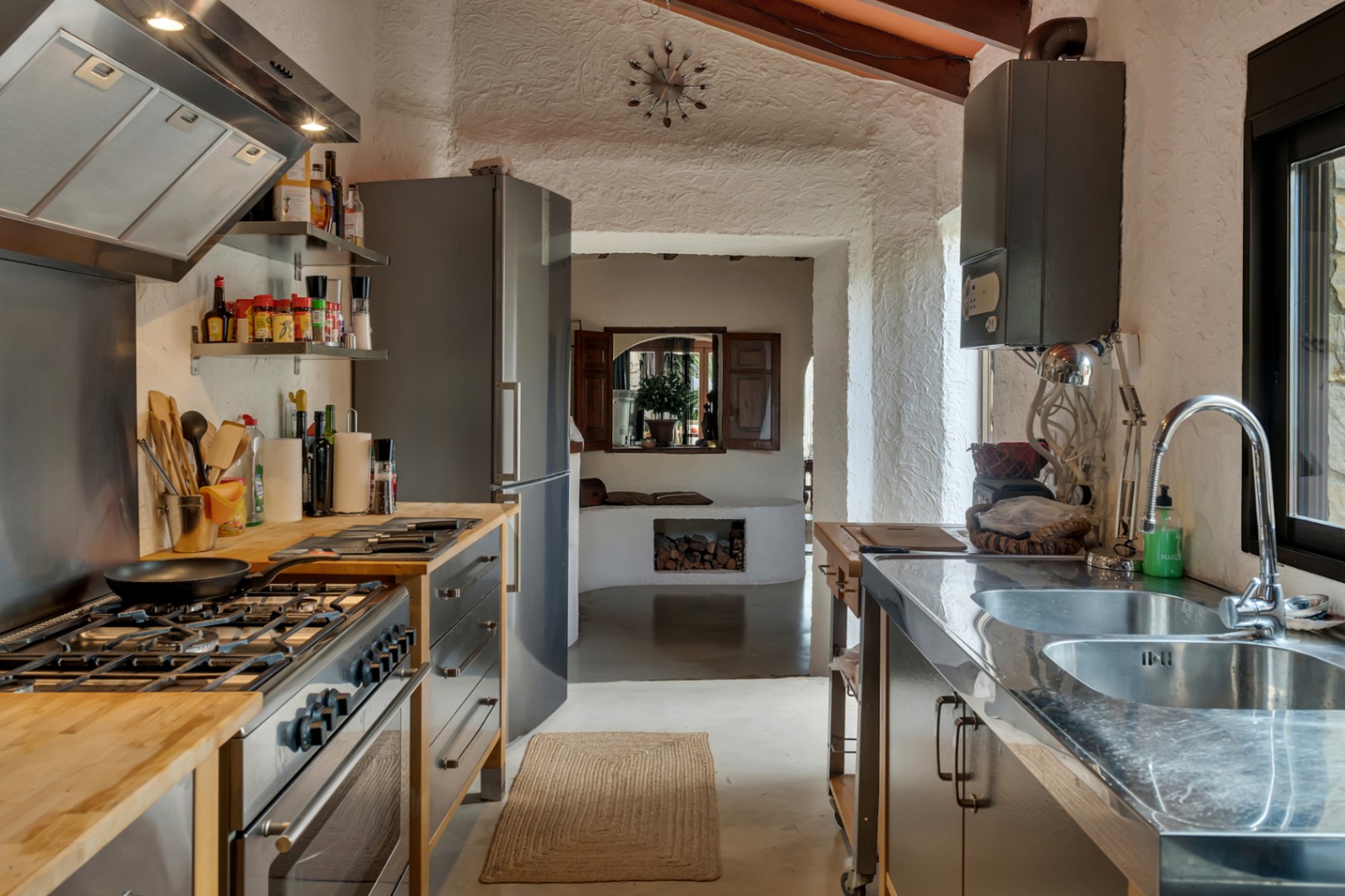 Cocina de estilo rústico-industrial con encimeras de madera y acero, equipada con electrodomésticos de alta gama y techos con vigas de madera vista.