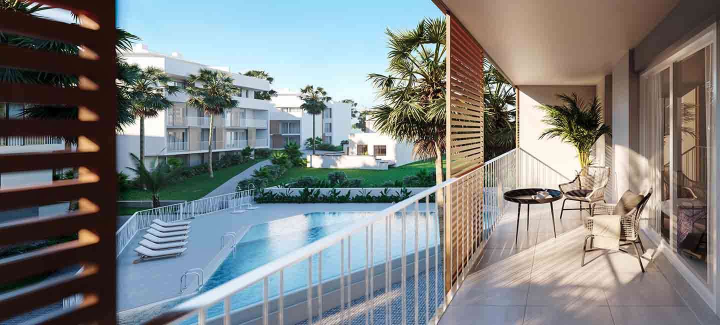 Terraza privada con suelo cerámico y barandilla blanca, con vistas directas a la piscina comunitaria y a los jardines con palmeras.