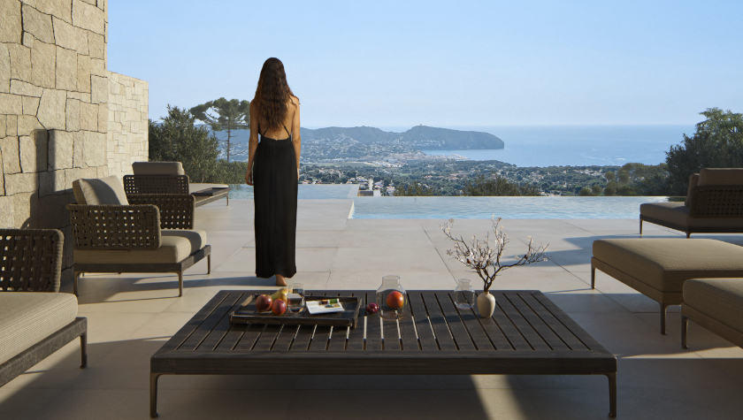 Terraza con piscina infinita y vistas panorámicas al mar. Destaca por sus muros de piedra natural, suelos de gran formato y mobiliario de exterior de diseño contemporáneo.