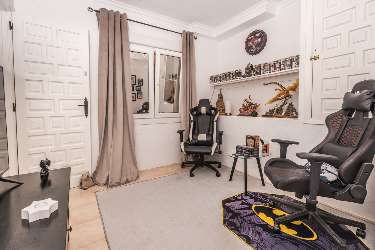 Habitación versátil con sillas de gaming, estantería para coleccionables y suelos de gres. Dispone de ventanas de doble acristalamiento y puertas blancas de estilo tradicional.