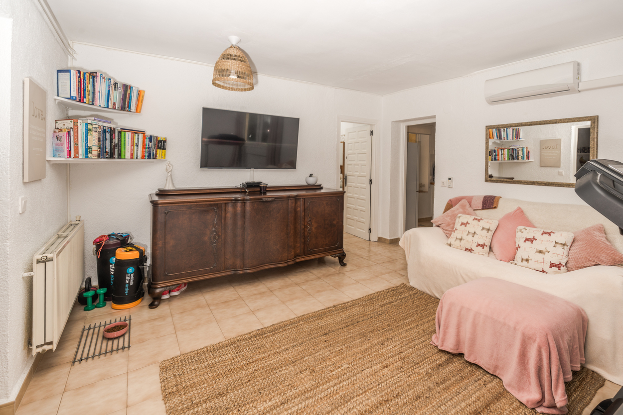 Sala de estar con aparador de madera clásico, televisión de pared y suelos cerámicos. Dispone de calefacción por radiador, aire acondicionado y alfombra de fibras naturales.