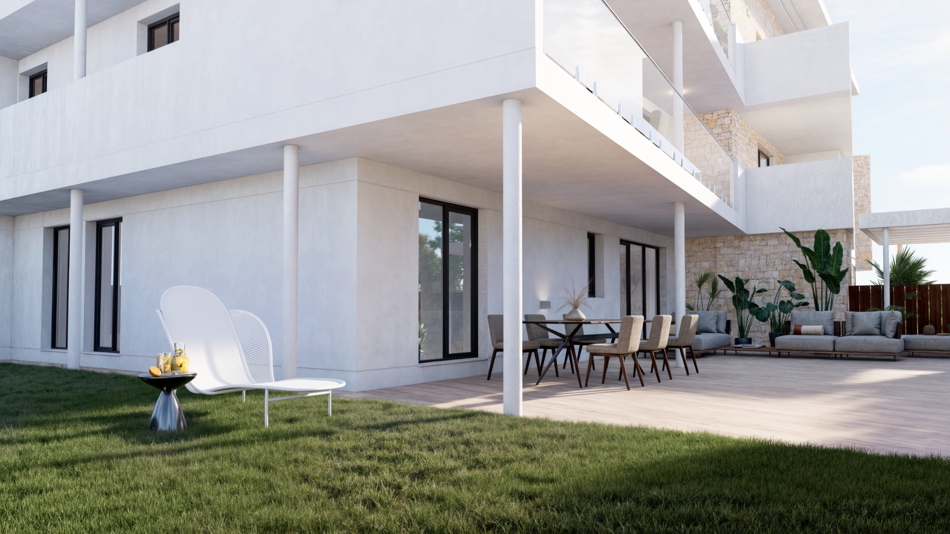Terraza en planta baja con suelo cerámico imitación madera, jardín privado y mobiliario exterior. La fachada blanca se combina con muros de piedra natural y barandillas de vidrio.