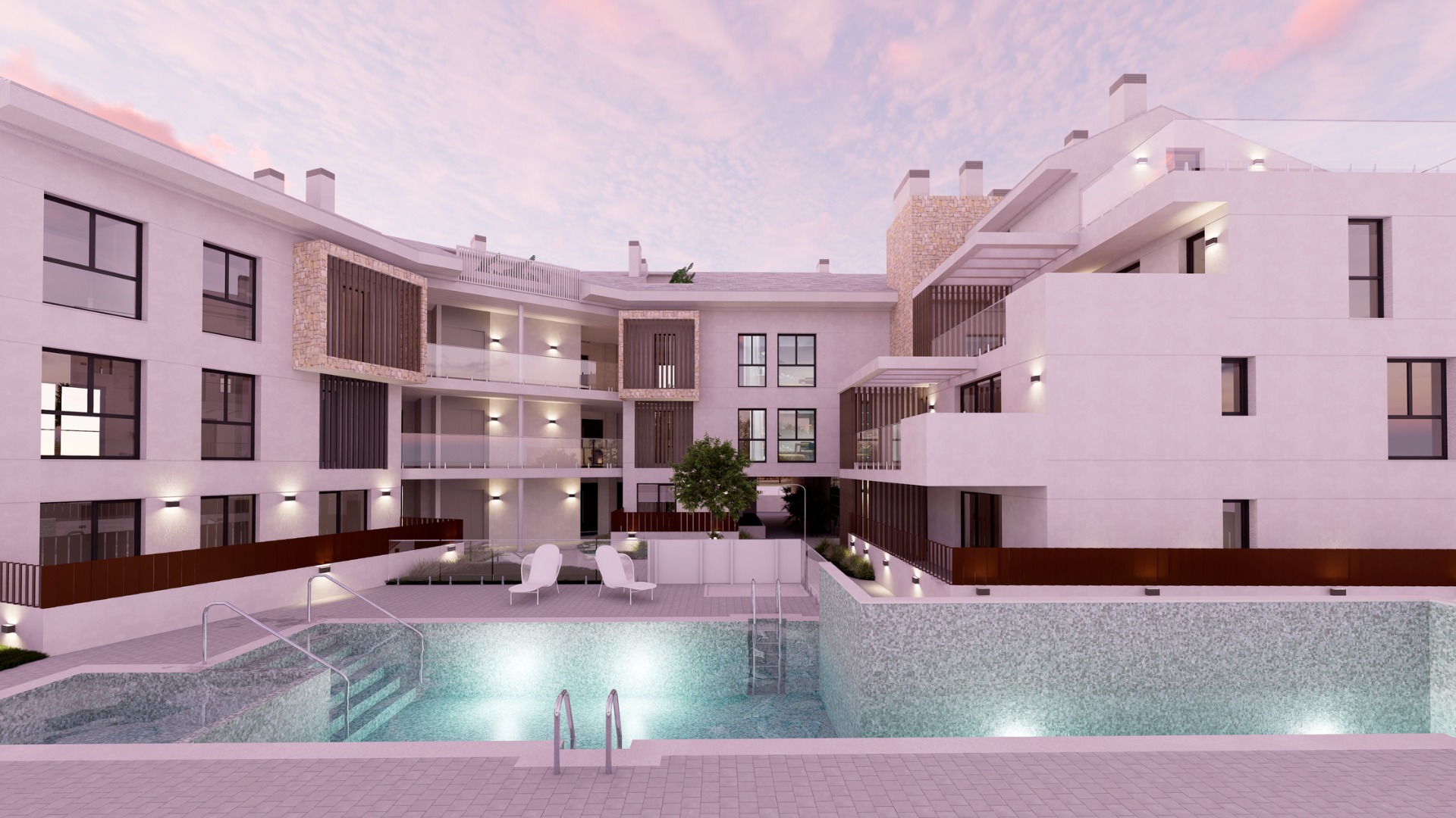 Vista exterior de la zona de piscina comunitaria con gresite, barandillas de cristal y fachadas blancas con detalles de piedra y lamas de madera al atardecer.