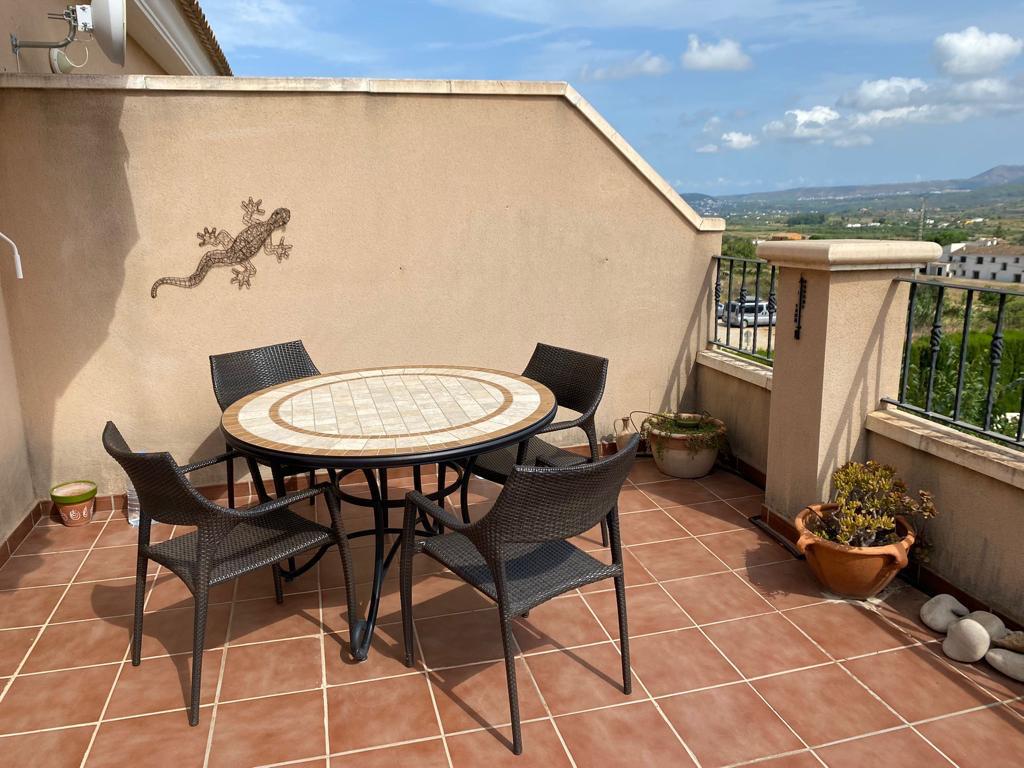 Terraza con baldosas de terracota, mesa de mosaico para cuatro comensales y vistas despejadas al paisaje rural de Jesús Pobre.