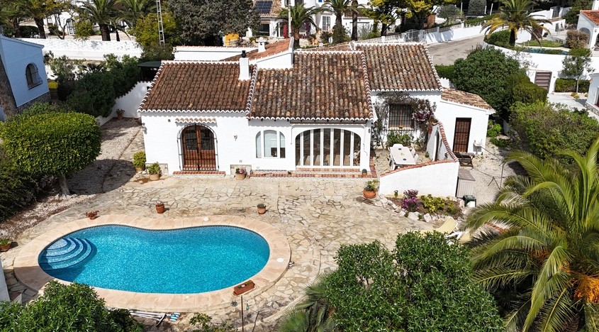 Vista aérea de la villa tradicional con piscina en forma de riñón, amplia terraza de piedra natural y arquitectura mediterránea con tejados de teja y fachadas blancas.