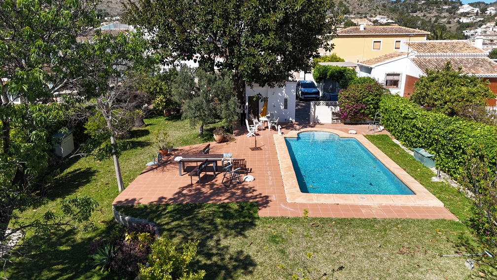 Piscina privada con terraza de terracota y zona de césped. Árboles maduros y setos ofrecen privacidad al área de comedor exterior y al jardín mediterráneo.