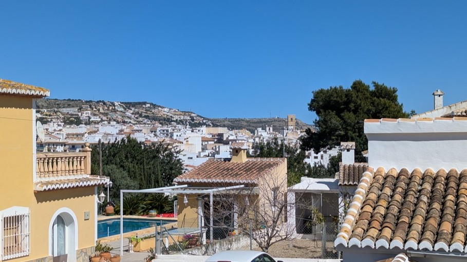 Vistas panorámicas desde la terraza superior hacia el casco antiguo de Jávea, destacando los tejados tradicionales, la piscina privada y el paisaje montañoso.