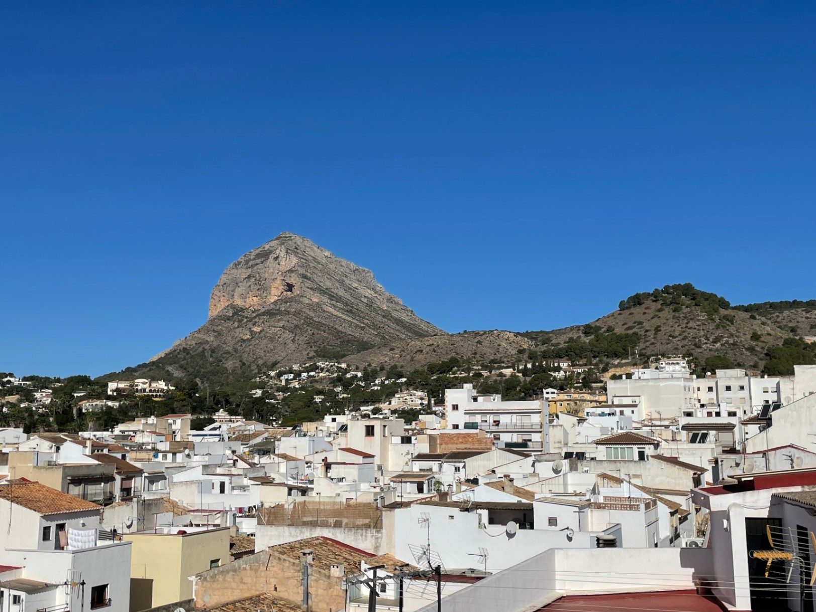 Vistas panorámicas desde la azotea hacia el macizo del Montgó y el casco urbano de Jávea, caracterizado por sus tradicionales fachadas blancas y tejados cerámicos.