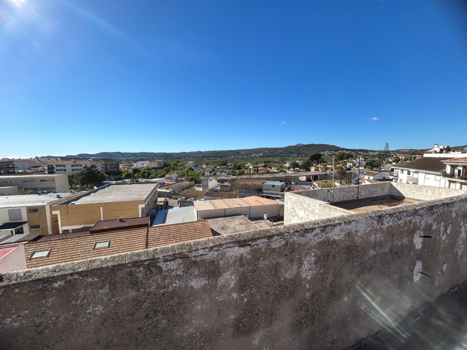 Vistas panorámicas desde la terraza comunitaria hacia el casco urbano y las montañas de Jávea, destacando la amplitud del entorno bajo un cielo despejado.