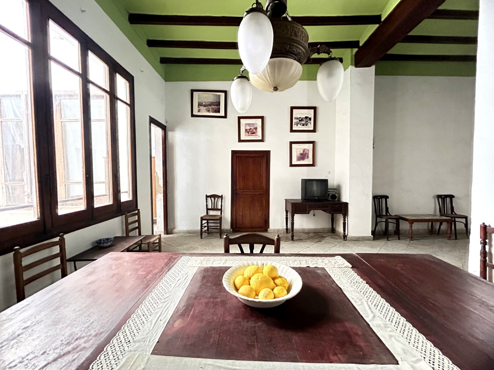 Comedor tradicional con techos altos de vigas de madera vistas, ventanales de época y una lámpara de araña clásica que aporta un carácter histórico único.