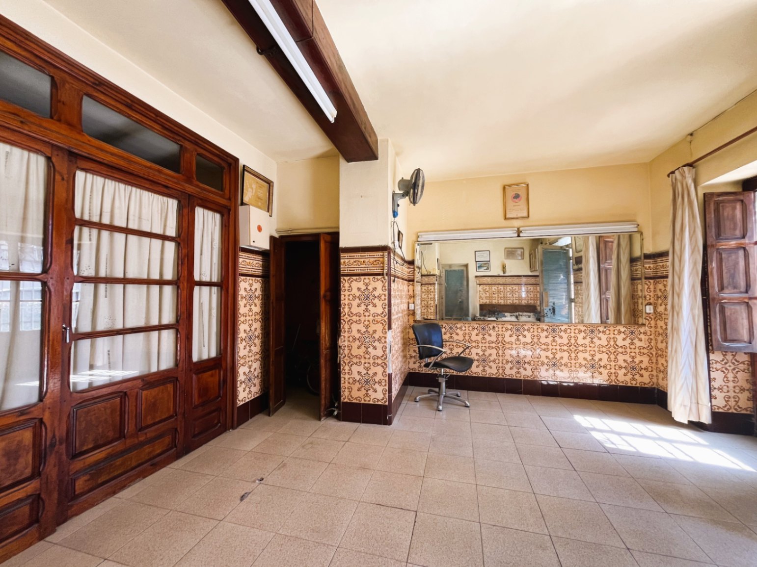 Estancia con azulejos tradicionales de época, vigas de madera vista y grandes puertas acristaladas que conservan el carácter histórico de la vivienda.