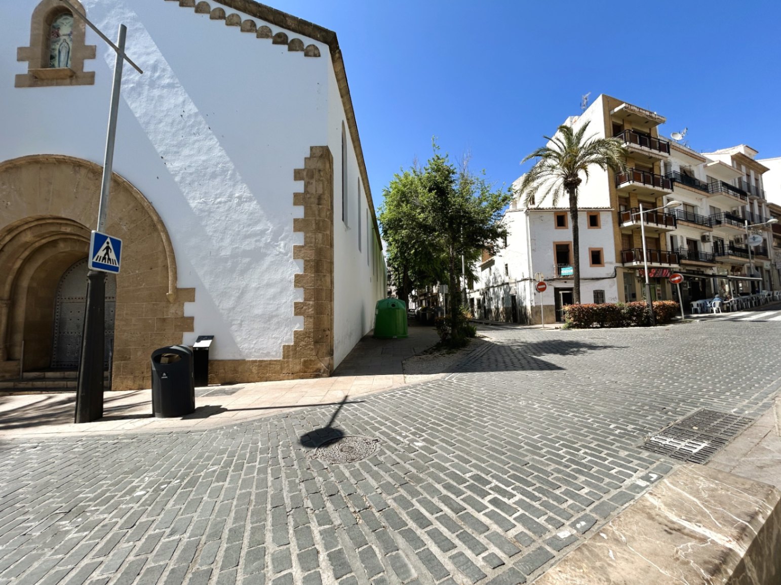 Vista exterior de la calle empedrada junto a un edificio histórico de piedra tosca, reflejando el entorno tradicional del casco antiguo de Jávea.