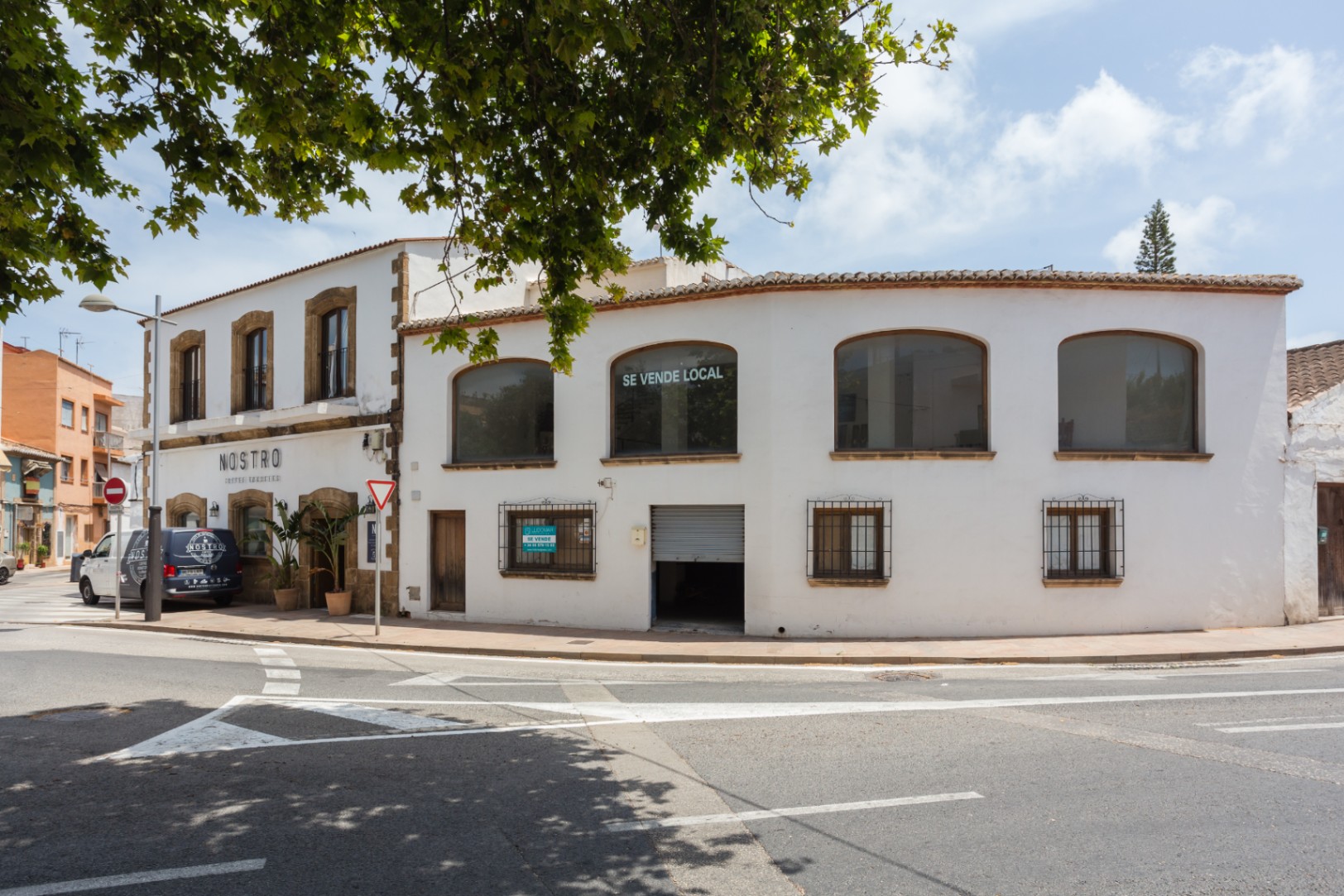 Fachada exterior de esquina en Jávea con marcos de piedra tosca tradicional, amplios ventanales en la planta superior y una estructura mediterránea de dos niveles.