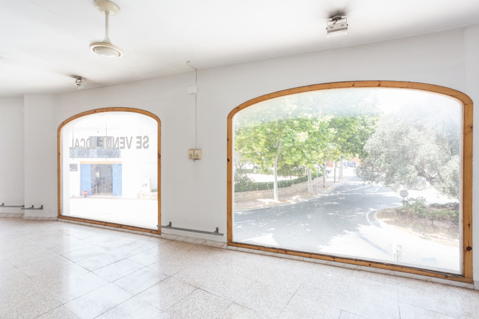 Planta principal con amplios ventanales en arco y marcos de madera que aportan luz natural. El espacio cuenta con suelos de terrazo y vistas despejadas a la arboleda exterior.
