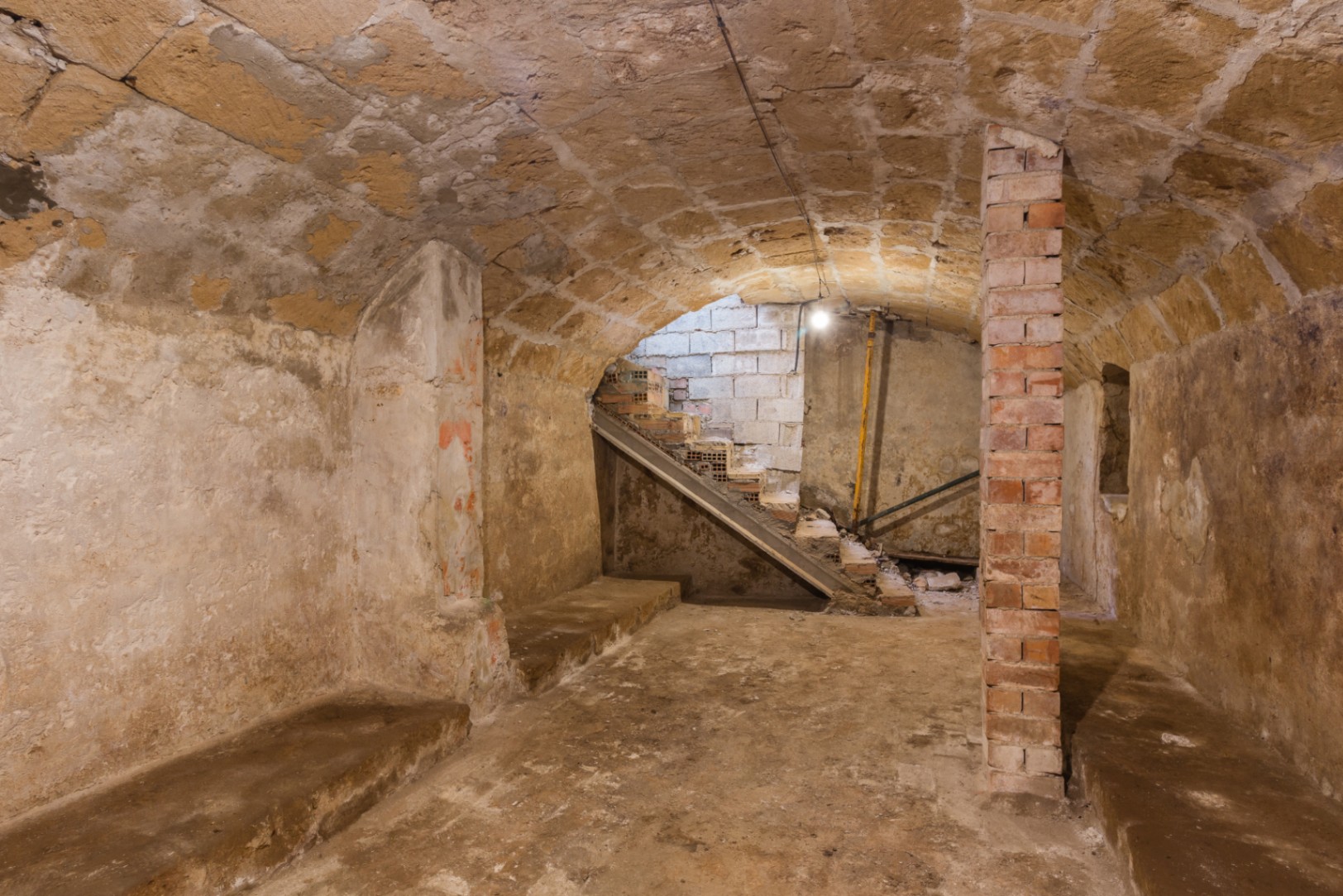 Sótano con techos abovedados de piedra tosca original y pilares de ladrillo visto. Espacio diáfano con acceso a escaleras, ideal para bodega o zona lounge.