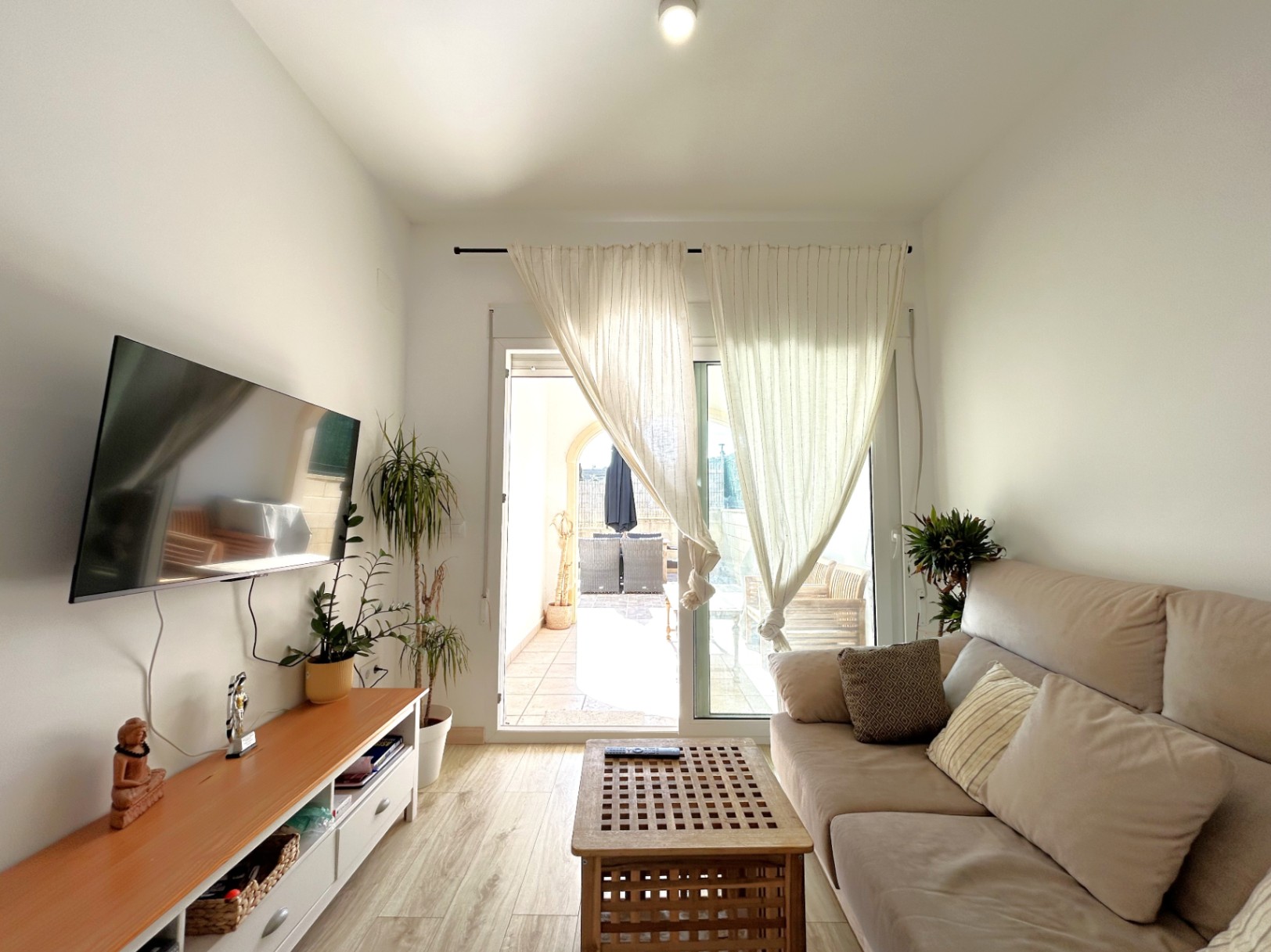 Salón luminoso con acceso directo a la terraza privada a través de puertas correderas, suelos de gres efecto madera y mobiliario funcional.