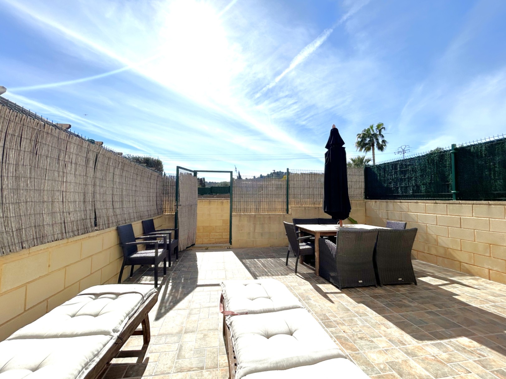 Terraza privada con orientación sur, pavimentada con gres y equipada con zona de comedor exterior, tumbonas y cerramiento perimetral de brezo para mayor privacidad.