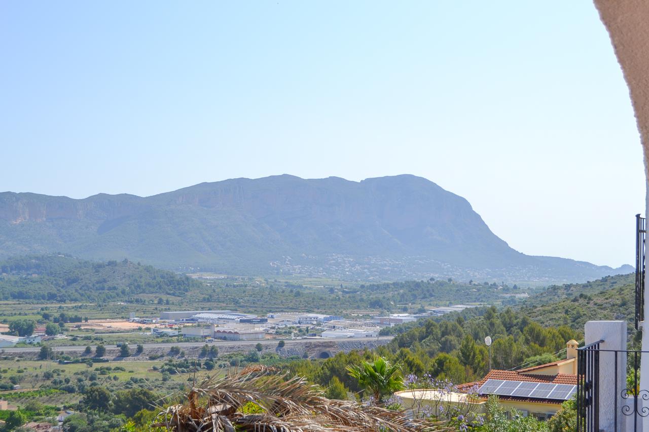 Vistas panorámicas despejadas hacia el valle y el macizo del Montgó desde la terraza elevada, rodeada de vegetación mediterránea.