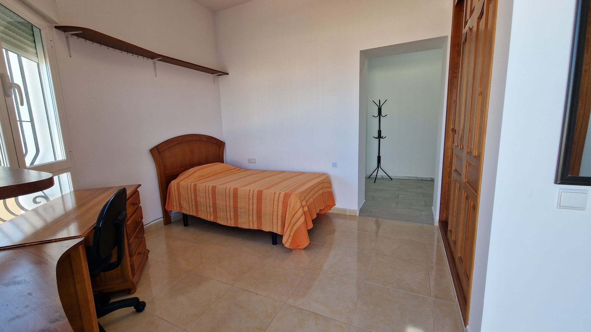 Dormitorio con cama individual, escritorio de madera y armario empotrado.