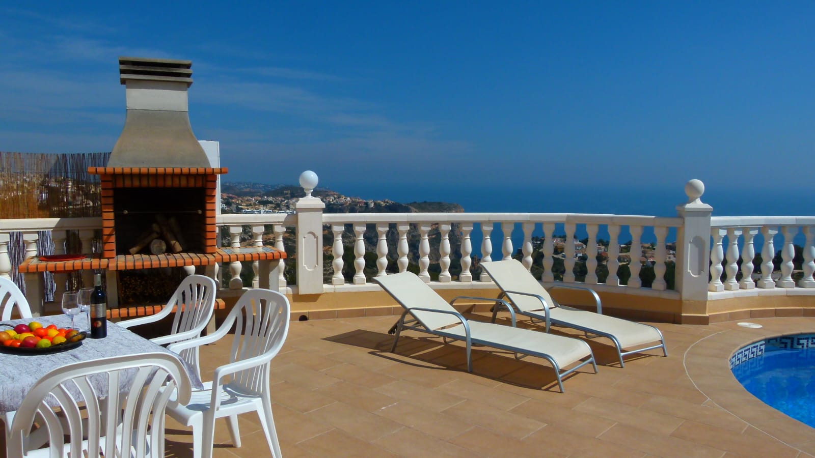 Terraza con barbacoa de ladrillo, tumbonas y vistas al mar desde Cumbre del Sol, Benitachell.