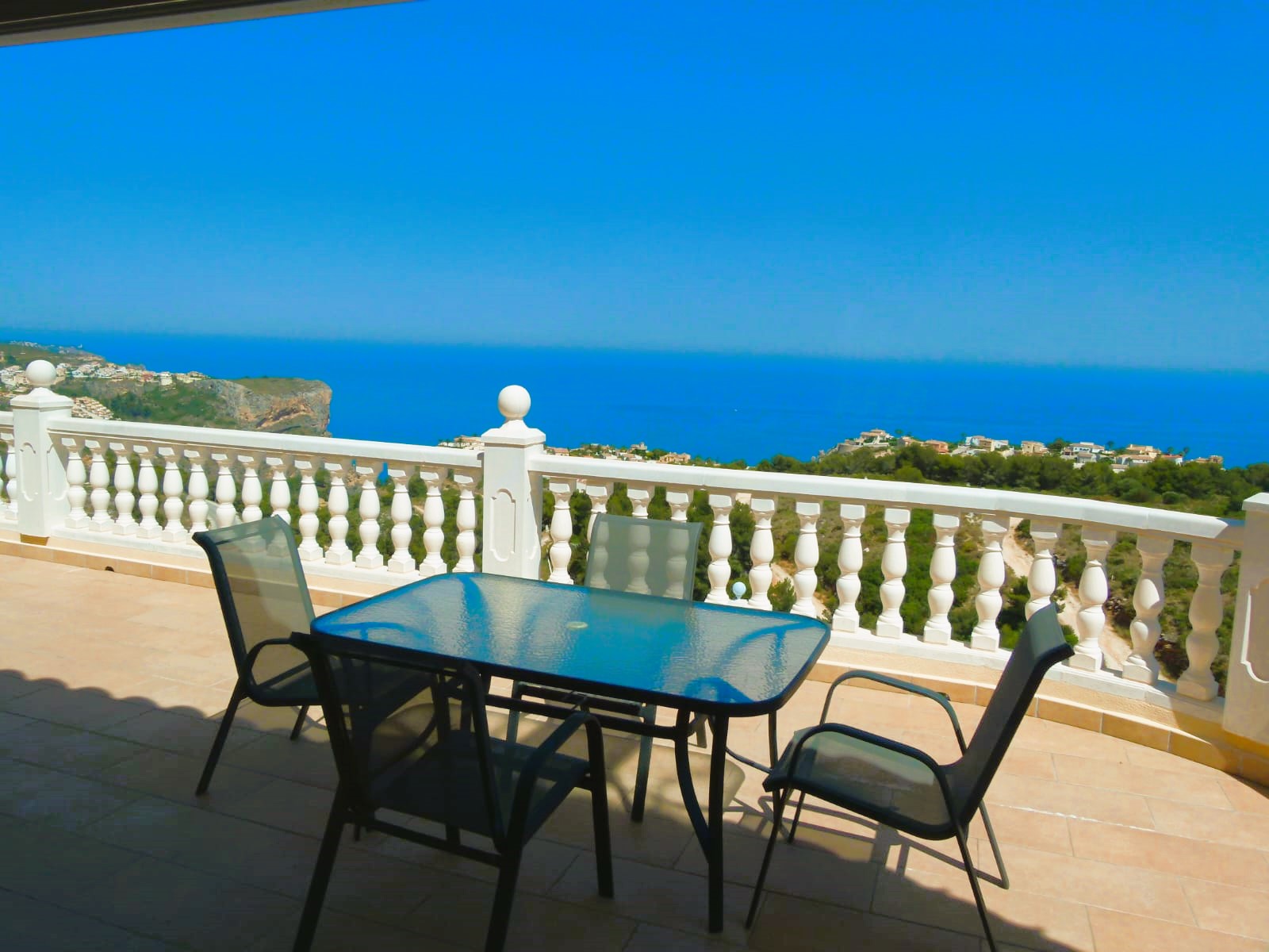 Terraza con mesa de cristal y vistas al mar en Cumbre del Sol. Barandilla blanca con balaustres.