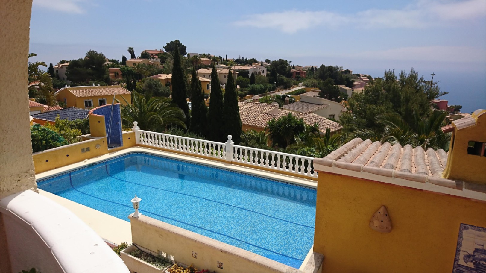 Piscina rectangular de 10x4 con gresite azul, rodeada por una balaustrada blanca y vistas panorámicas al mar y al entorno residencial de Cumbre del Sol.