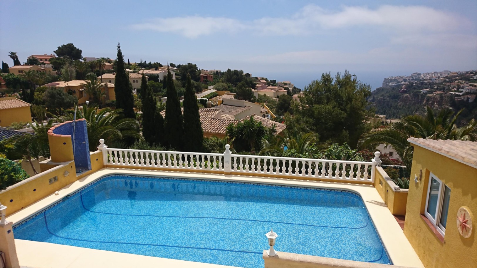 Piscina rectangular de 10x4 metros con gresite azul, rodeada por una balaustrada blanca y vistas panorámicas al mar Mediterráneo y los acantilados de Cumbre del Sol.