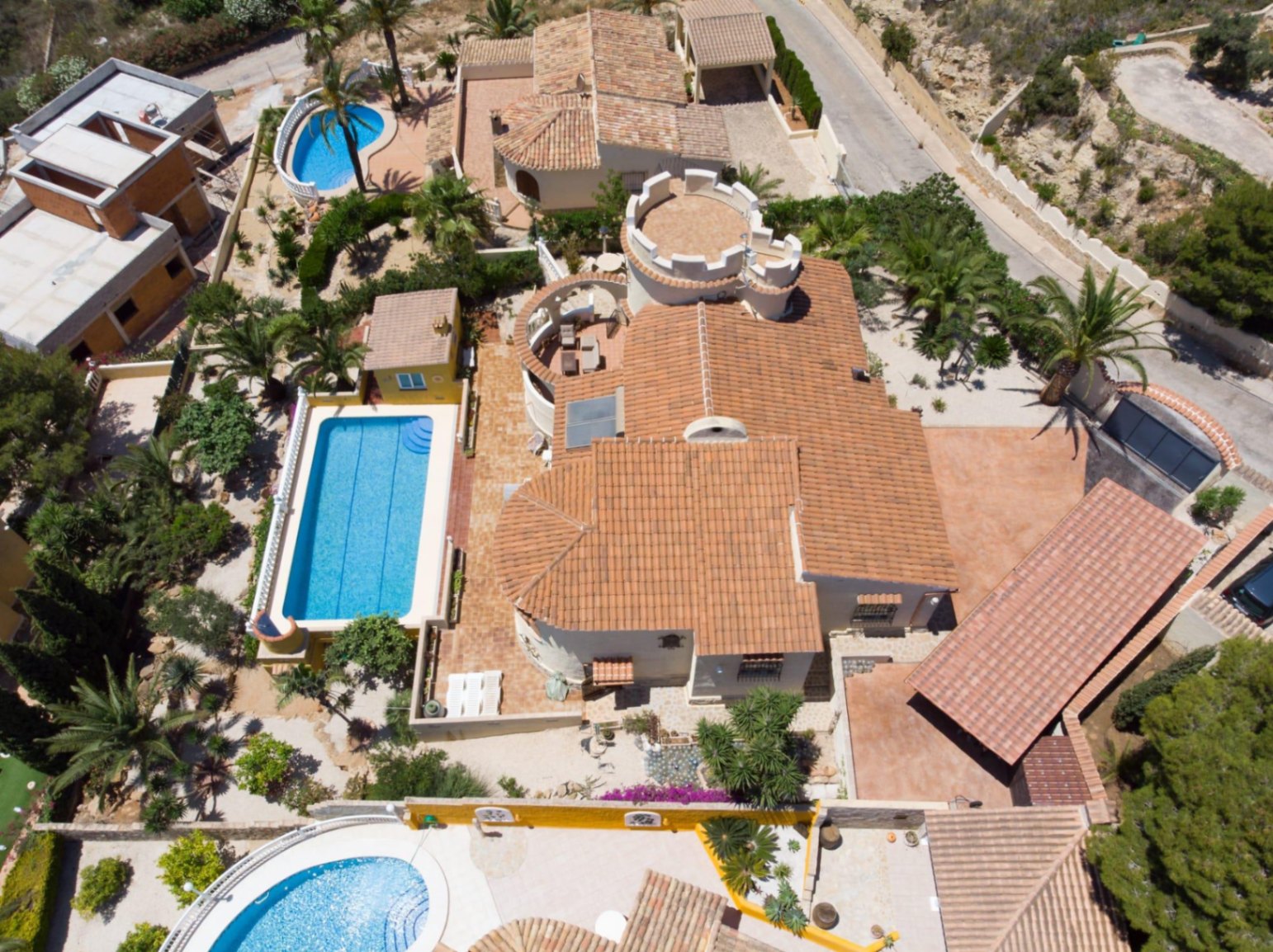 Vista aérea de la villa que destaca su arquitectura con torre, la piscina de 10x4 metros y las amplias terrazas rodeadas de vegetación mediterránea.
