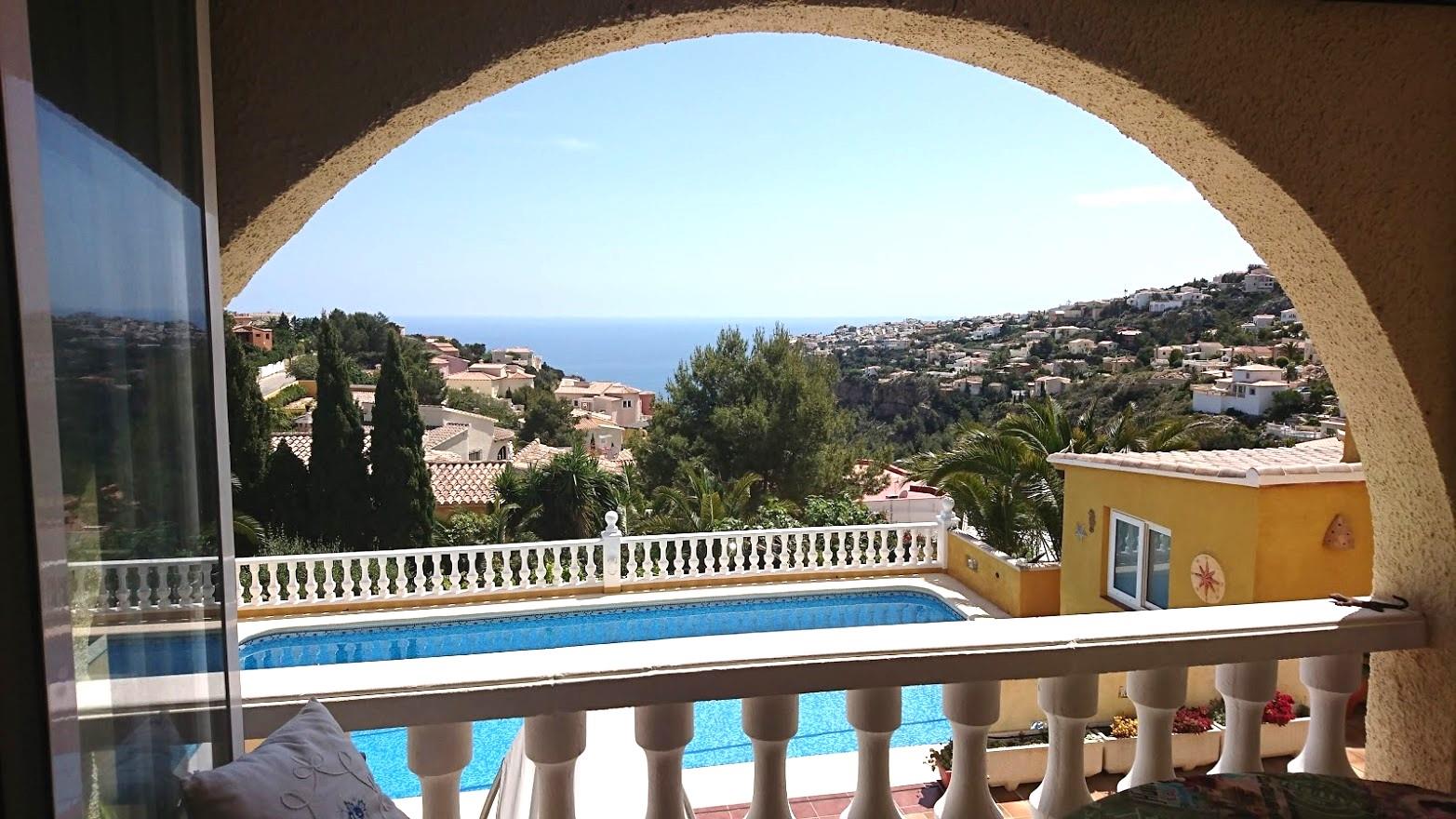 Vista desde la naya arqueada hacia la piscina privada y el mar Mediterráneo, enmarcada por una balaustrada blanca y vegetación local.