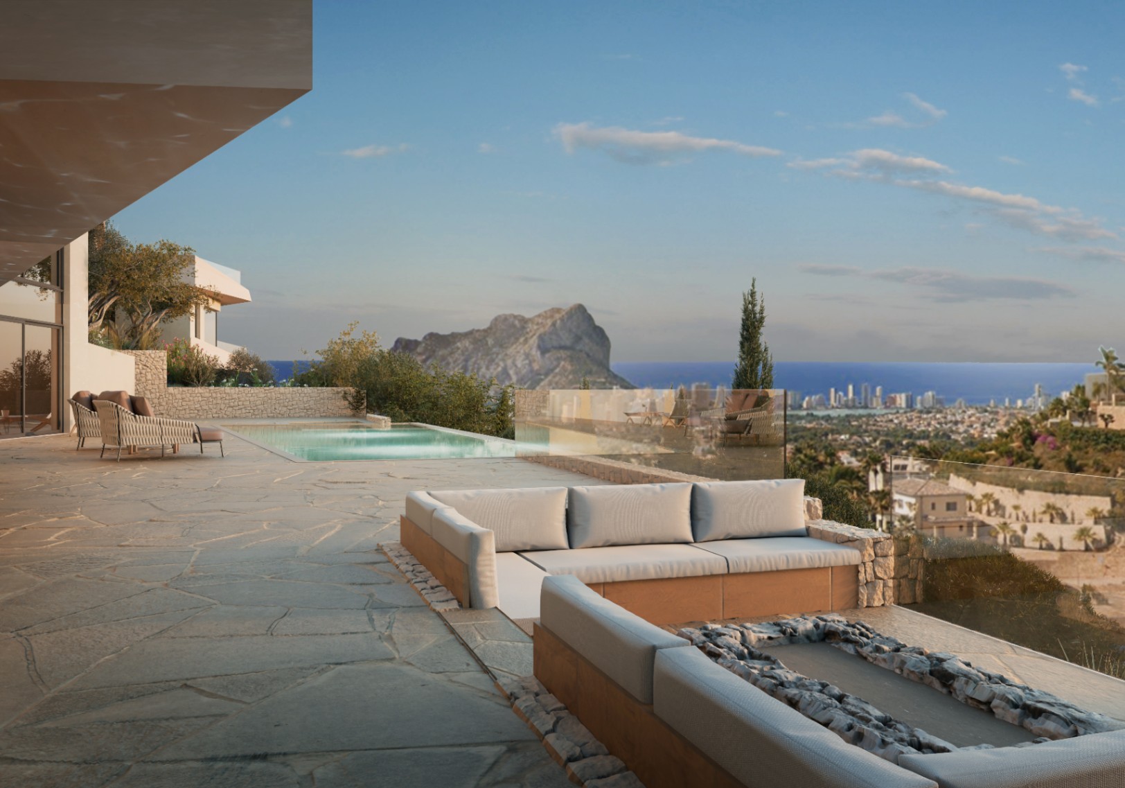 Terraza con piscina y vistas al mar, mobiliario de exterior con base de piedra y pavimento de losas irregulares.