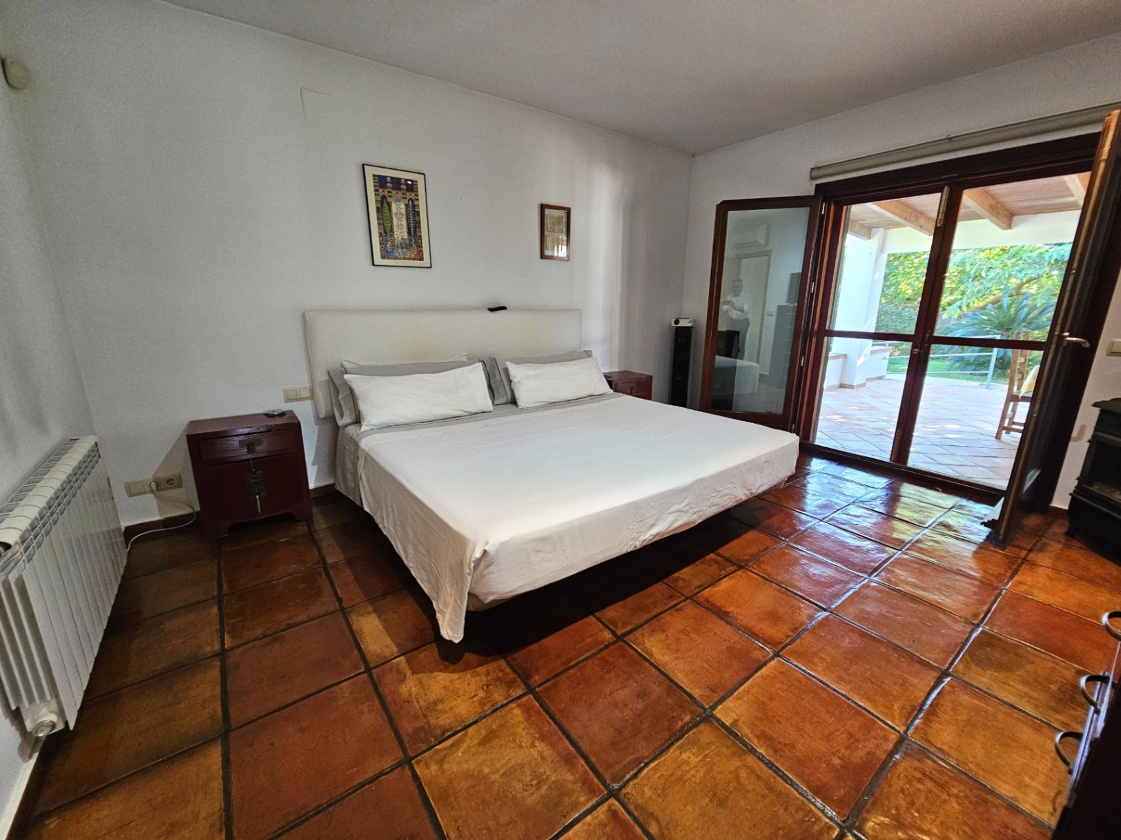 Dormitorio principal con suelos de barro hechos a mano y acceso directo a la naya. Grandes ventanales de seguridad ofrecen vistas al jardín y abundante luz natural.