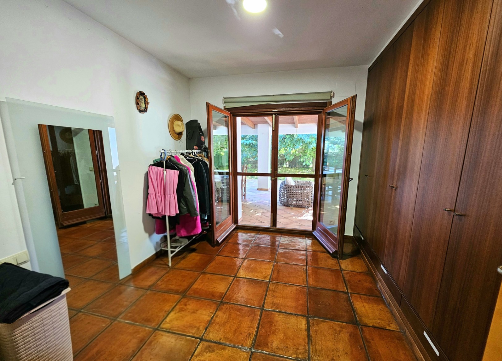 Vestidor con amplios armarios empotrados de madera, suelos de barro artesanal y acceso directo a la naya exterior a través de puertas acristaladas.