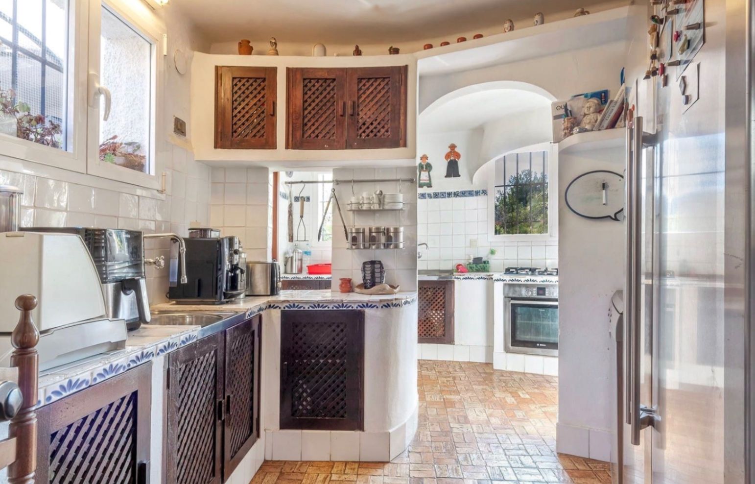 Cocina de estilo rústico con armarios de madera oscura y celosía, encimeras con azulejos decorativos azules y suelos de barro cocido tradicionales.