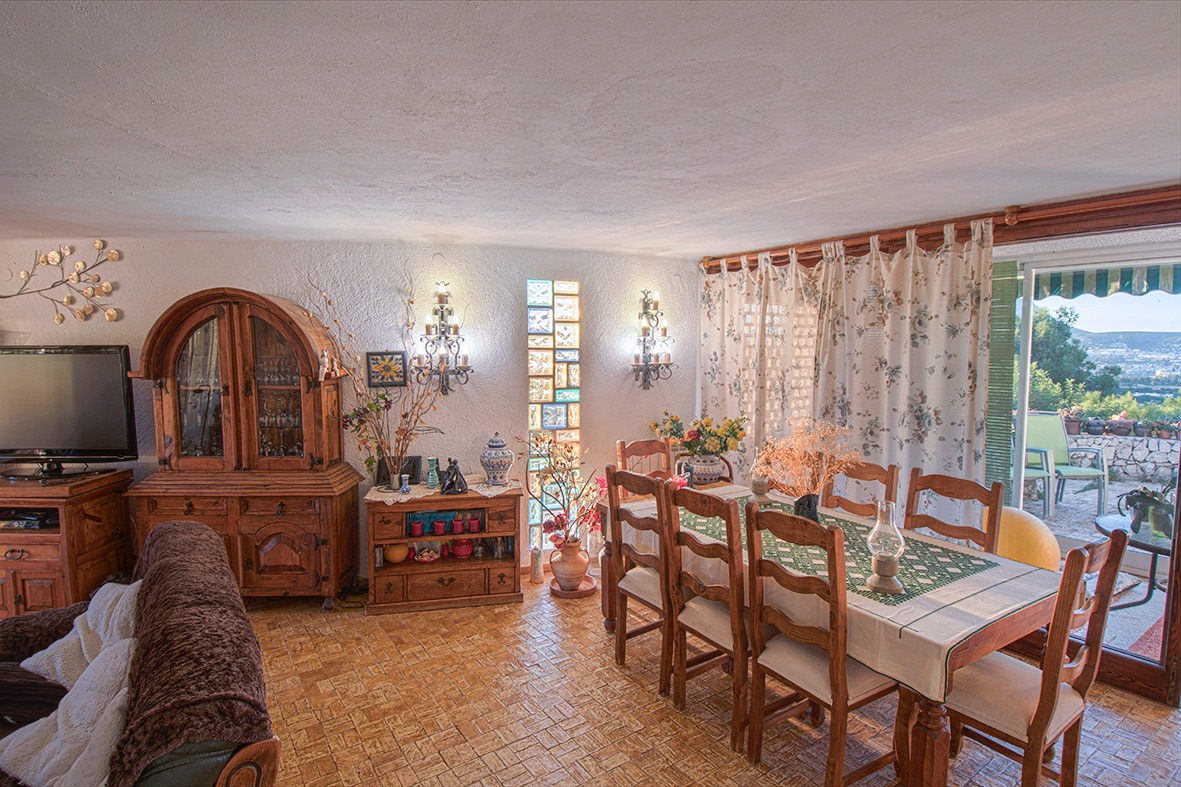 Comedor rústico con muebles de madera maciza, suelo cerámico y acceso directo a la terraza mediante un gran ventanal con vistas al valle.
