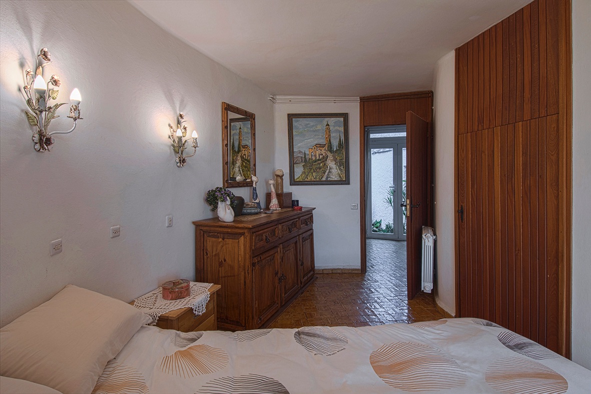Dormitorio de estilo rústico con armarios empotrados de madera, suelos de gres y apliques decorativos que aportan una iluminación cálida.
