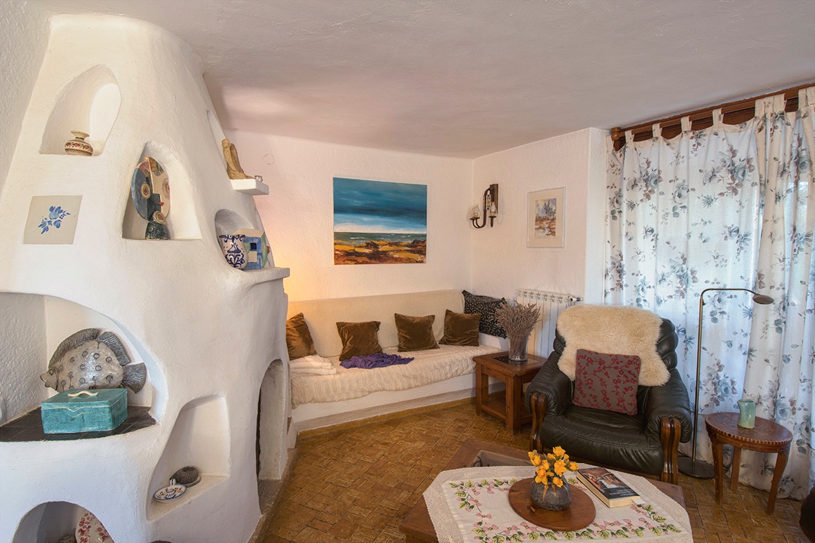 Salón de estilo rústico con una chimenea escultórica de obra blanca con hornacinas decorativas, suelos de gres tradicional y mobiliario acogedor.
