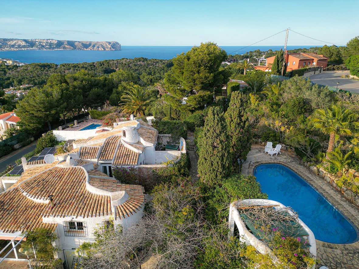 Vista aérea de la villa tradicional con tejados de teja, piscina privada y vistas panorámicas al mar Mediterráneo y la costa de Jávea.