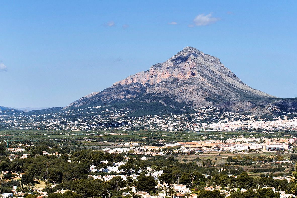 Vistas panorámicas al macizo del Montgó y al valle de Jávea bajo un cielo despejado, destacando la vegetación mediterránea y las zonas residenciales.