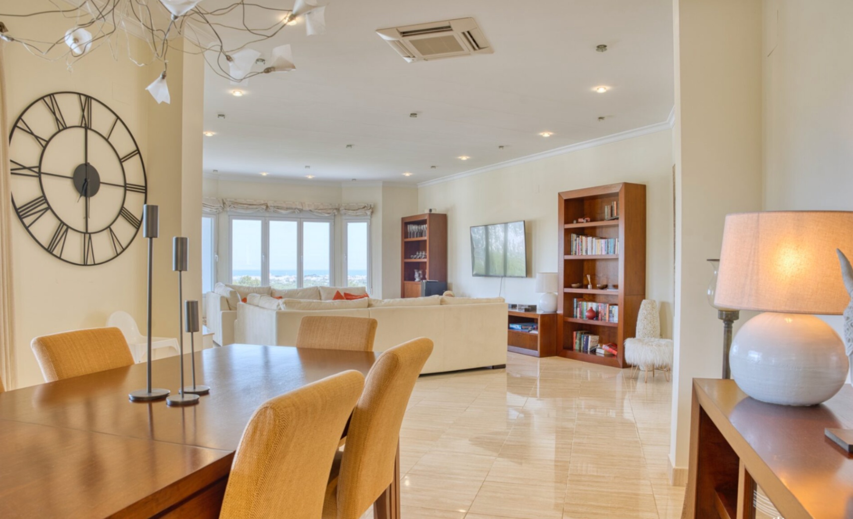 Amplio salón-comedor de planta abierta con suelos de mármol pulido, mobiliario de madera noble y grandes ventanales con vistas panorámicas al mar Mediterráneo.