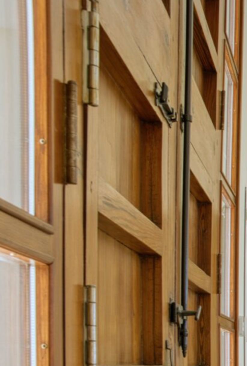Detalle de carpintería en madera maciza con herrajes metálicos tradicionales y sistema de cierre de falleba, reflejando la calidad de los acabados interiores.